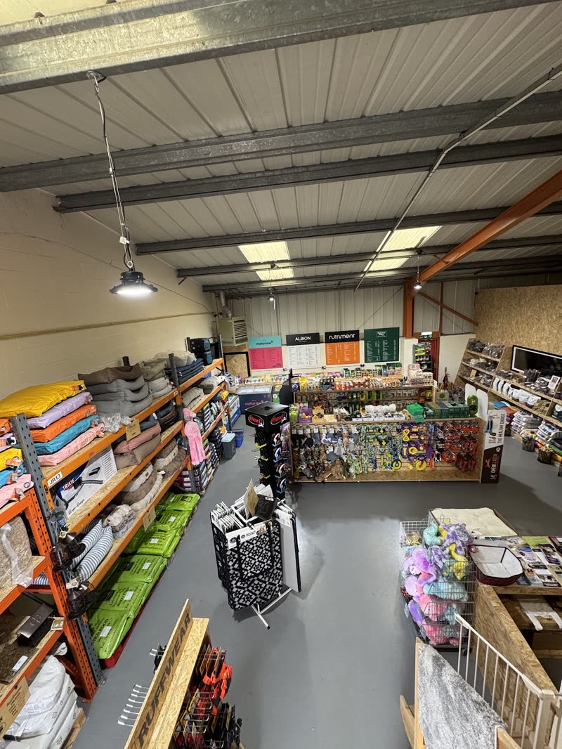 Wide view down the length of the warehouse shop floor, racking and aisle under industrial lighting