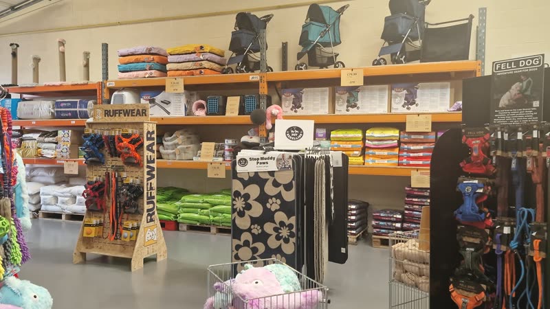 Aisle of accessories with hanging leads and collars, coats and folded bedding on racking